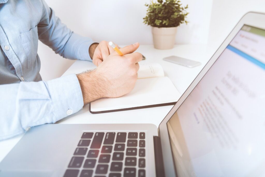 Man taking notes and on laptop